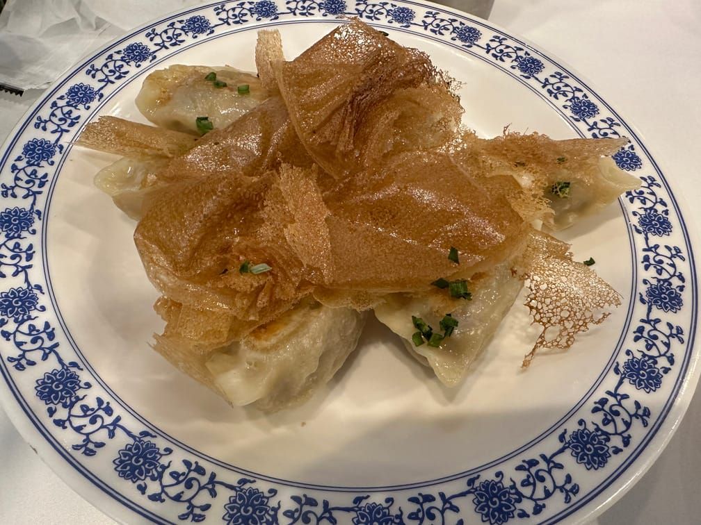 식탁 위 그릇에 만두와 얇게 튀겨진 전분막이 올라가 있는 사진