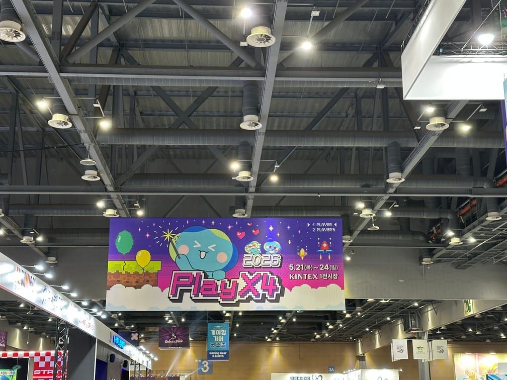 실내 행사장 천장에 2026 PlayX4라고 적힌 현수막이 매달려 있는 사진.