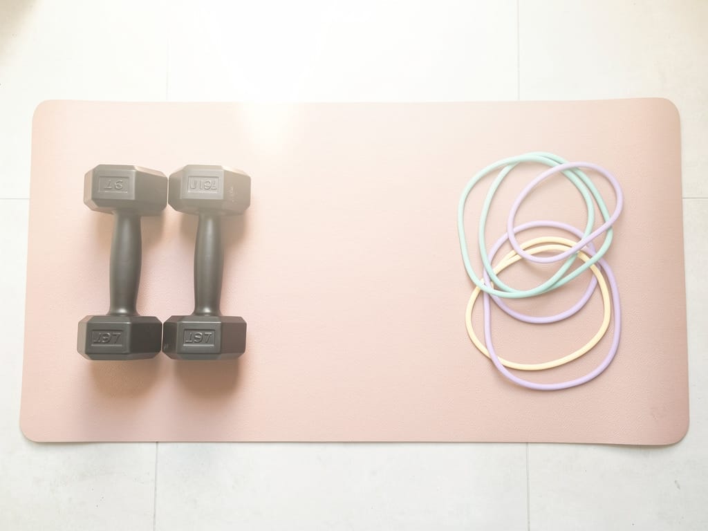 Dumbbells and resistance bands on a pastel yoga mat