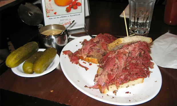 A rather packed pastrami sandwich, with complimentary pickles. Photograph: Wikimedia Commons