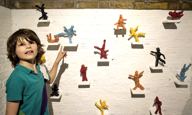 A young artist stands beside the 'oil and wire figures dipped in acrylic paint'