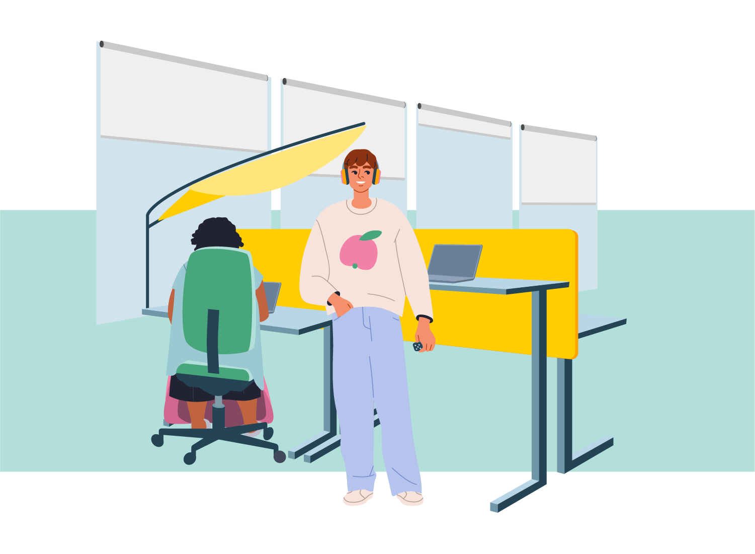 A smiling young adult at an office workplace. They are wearing headphones and are holding a small fidget in one hand. Behind them is a standing desk. Next to them cooworker is using a laptop at a sitting workstation.