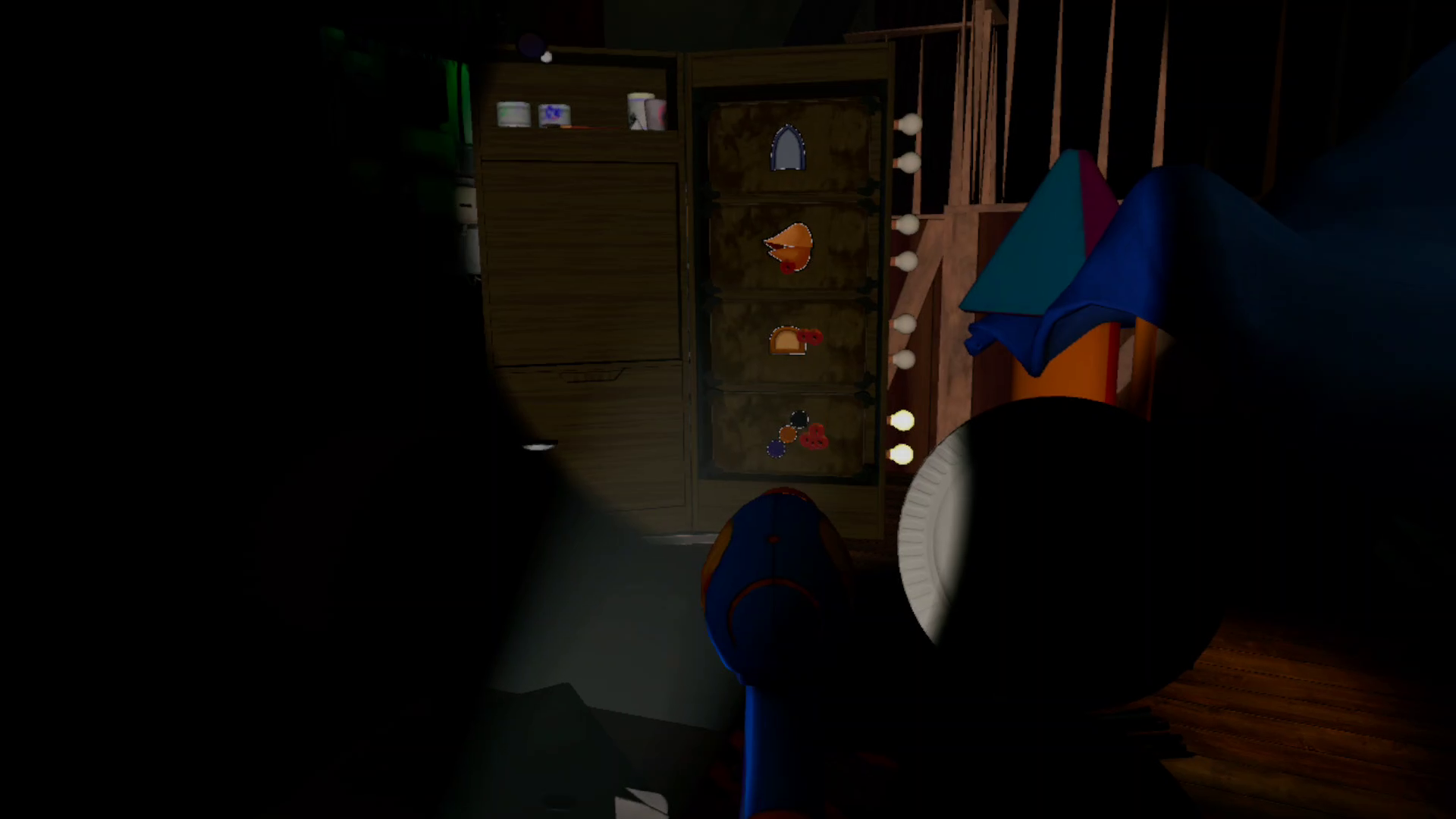 A flashlight and dart gun are held in hand in a pitchblack room of arts and crafts supplies