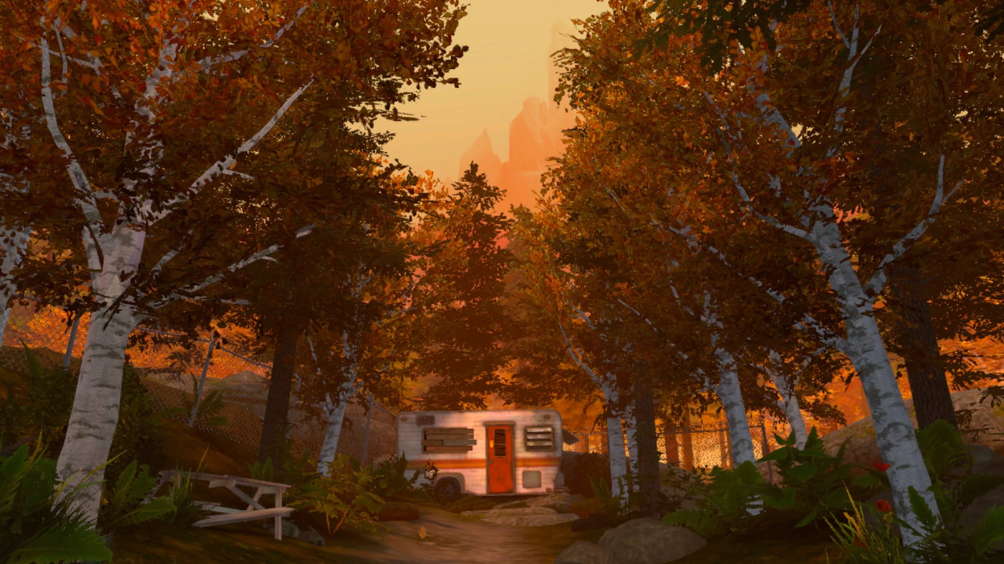 An RV with a red door in a clearing of trees during the fall. A broken picnic bench is in the foreground.