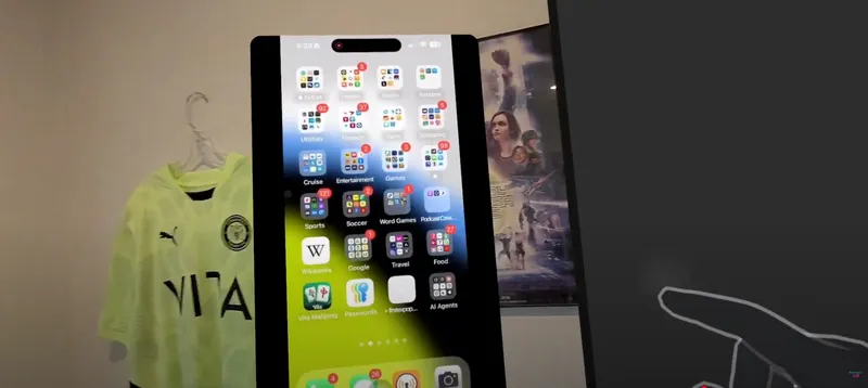 Mixed reality view of a virtual smartphone interface floating in front of a hand-tracked finger, with a yellow soccer jersey hanging on a wall and a movie poster in the background.