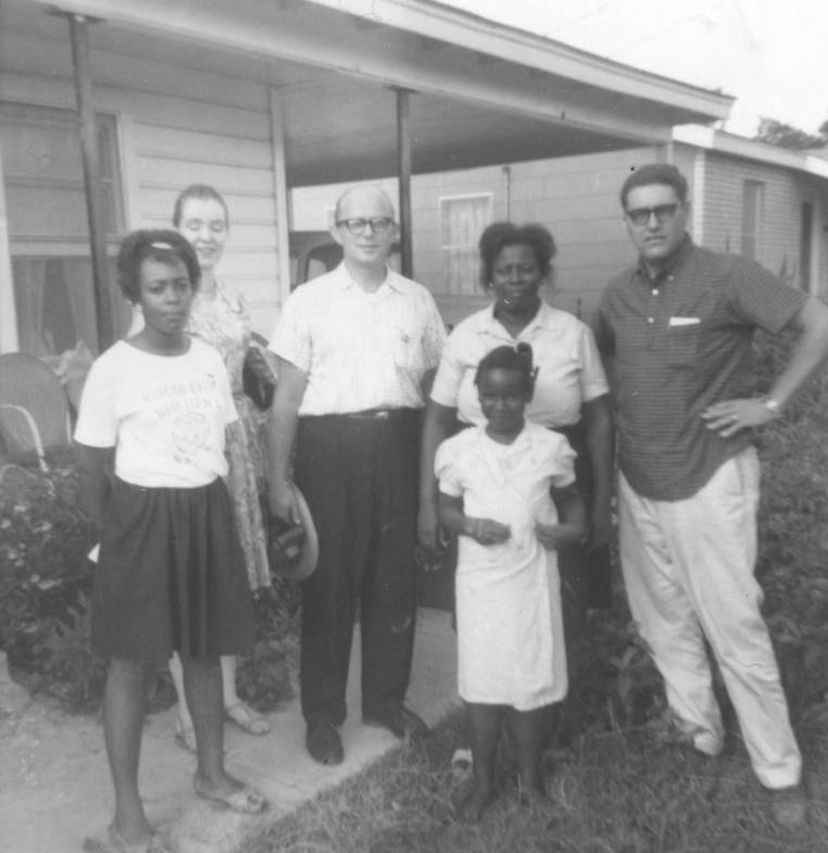 A family of Black Mississippians stands with white Freedom Summer volunteers in a black and white photo