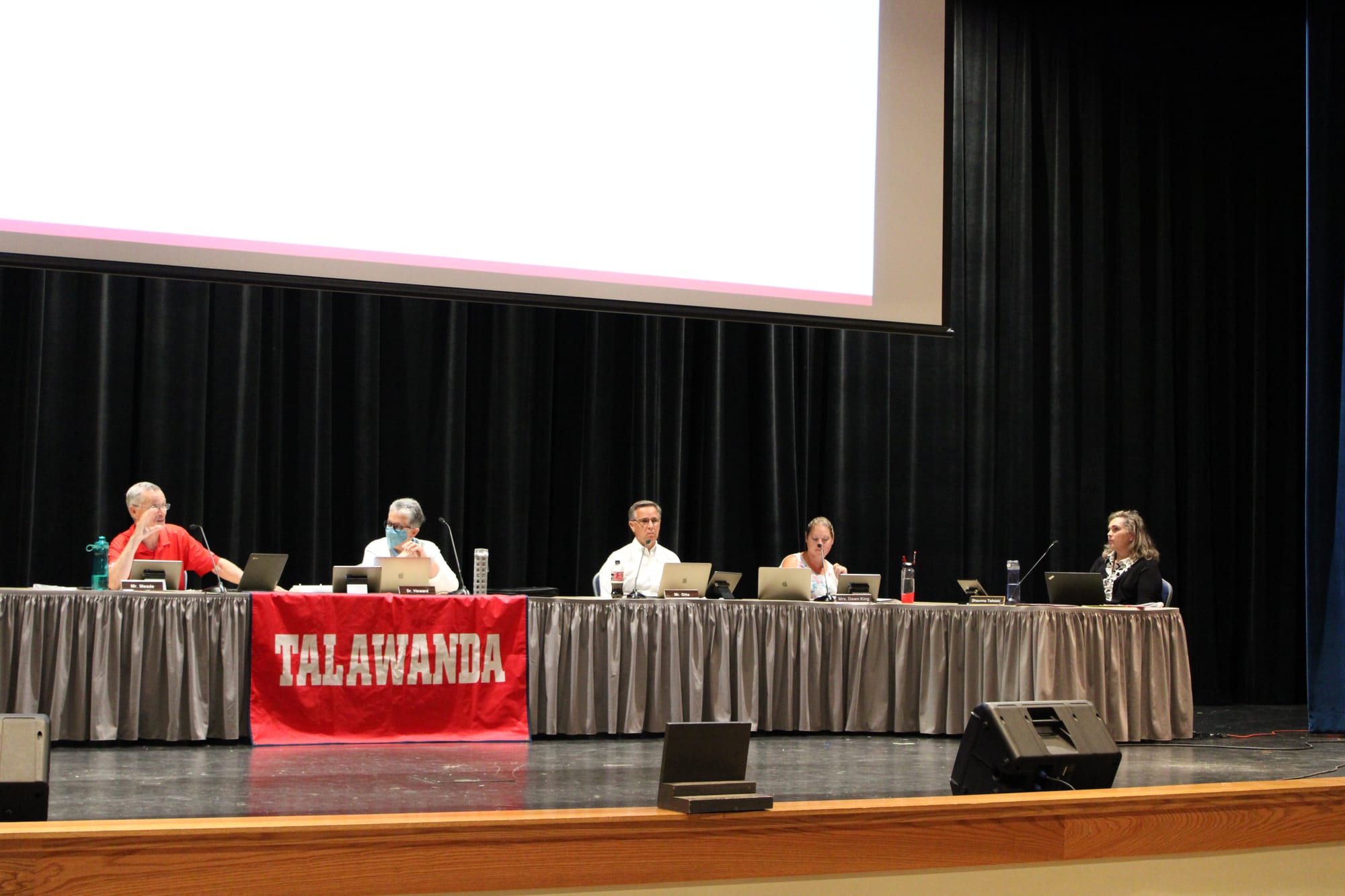 Five people sit at a table on a stage, with a banner in front that reads "Talawanda."