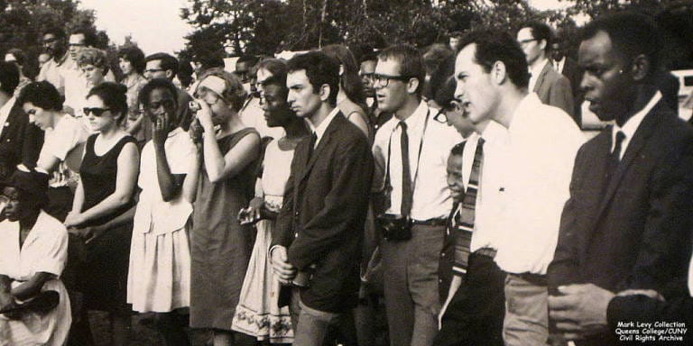 A group of young adults stands looking to the left in a black and white photo