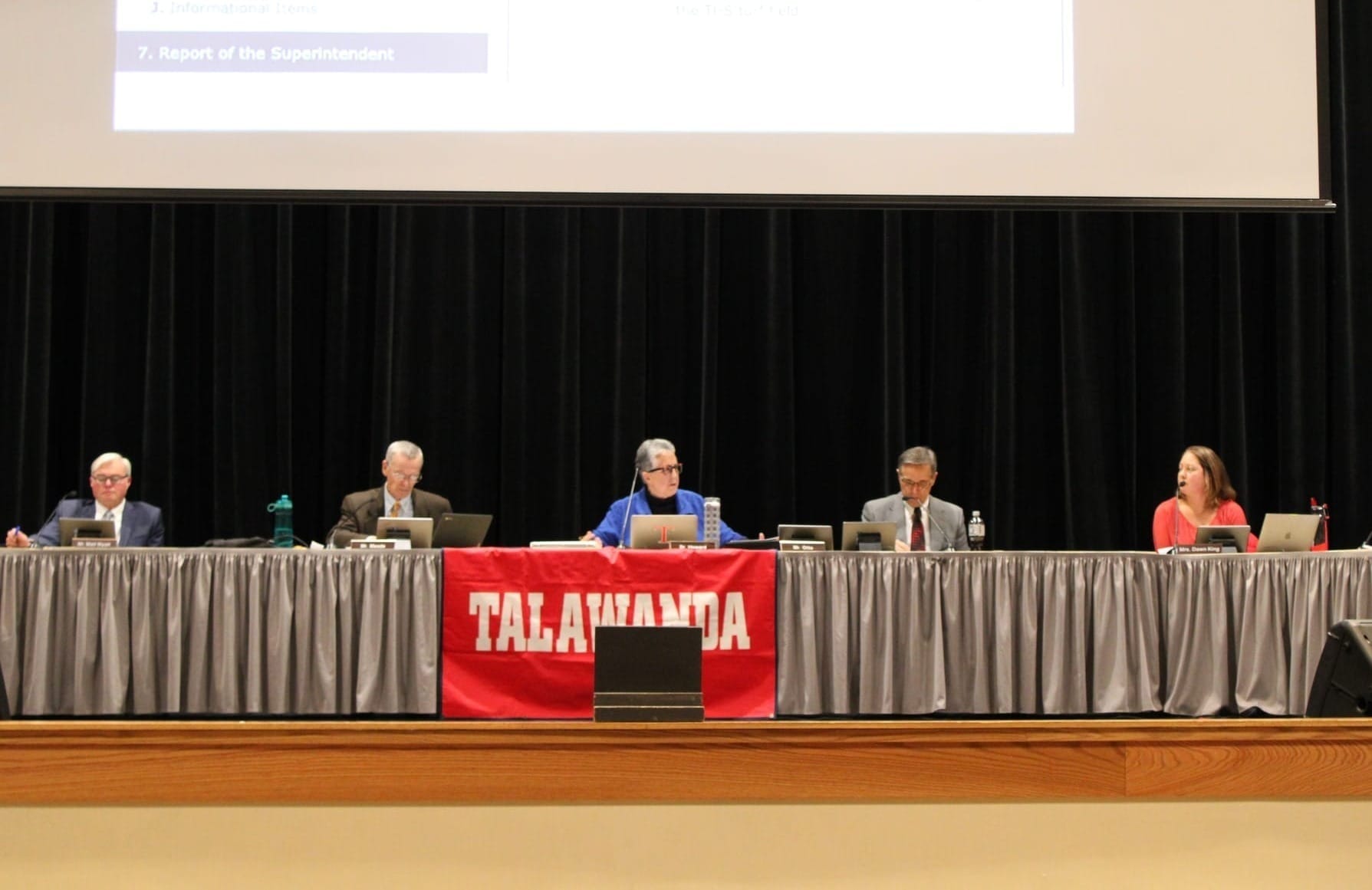 The five-member Talawanda School Board sits on stage behind a table