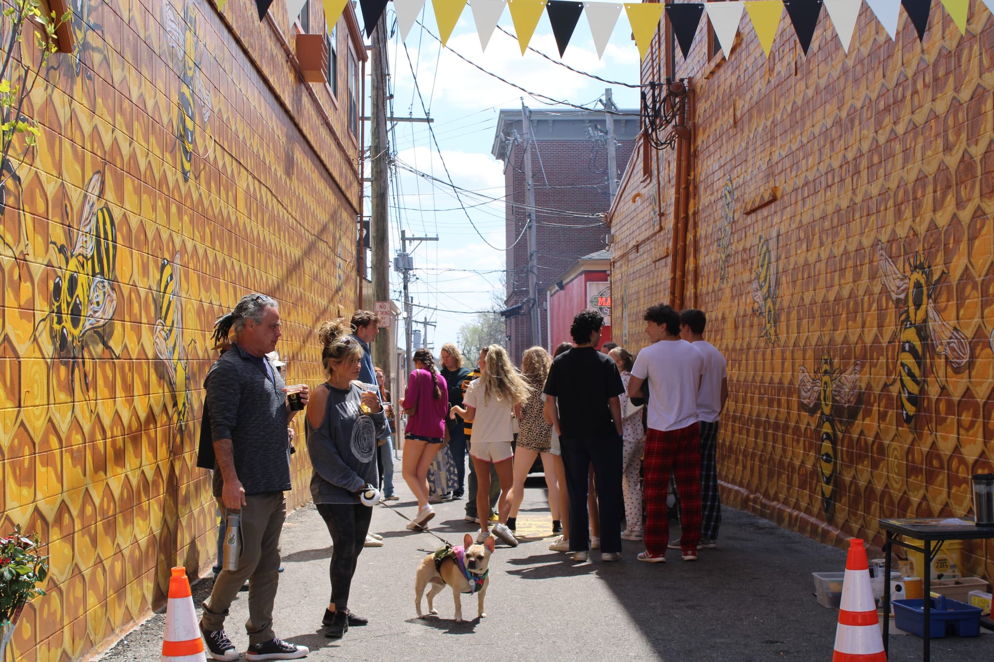 Multiple people stand in the Oxford Hive mural alley, posing for pictures