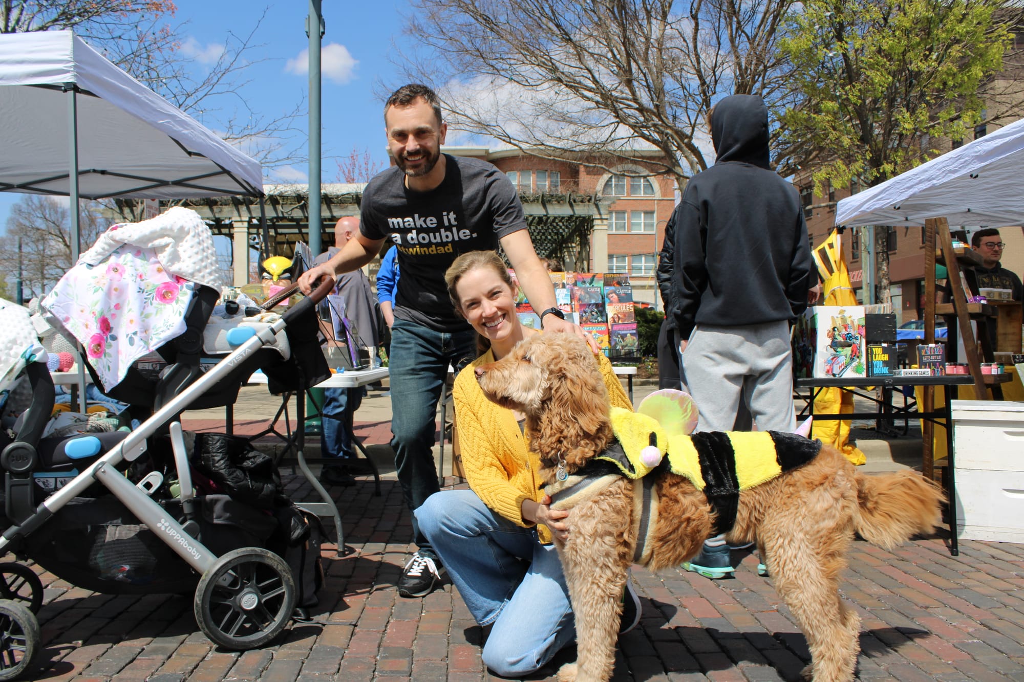 Erick and Laura Macek pose with Caliee, a therapy dog wearing a bee costume