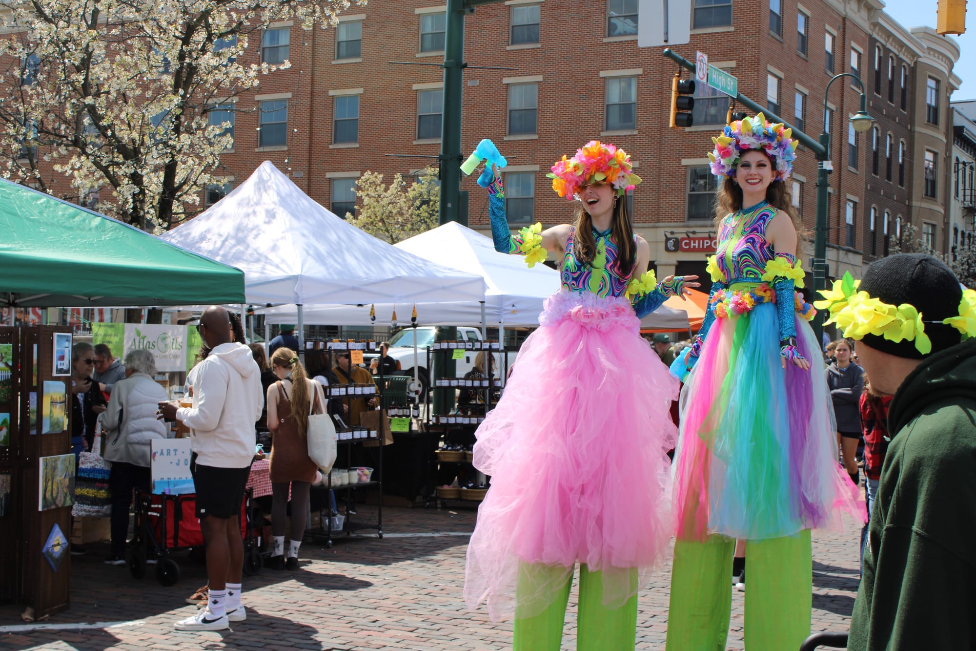 Two women on stilts dressed in colorful spring costumes