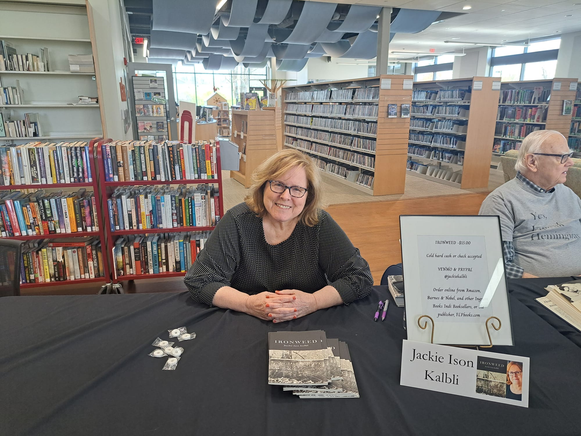 Jackie Ison Kalbi sits behind a table with copies of her book on display
