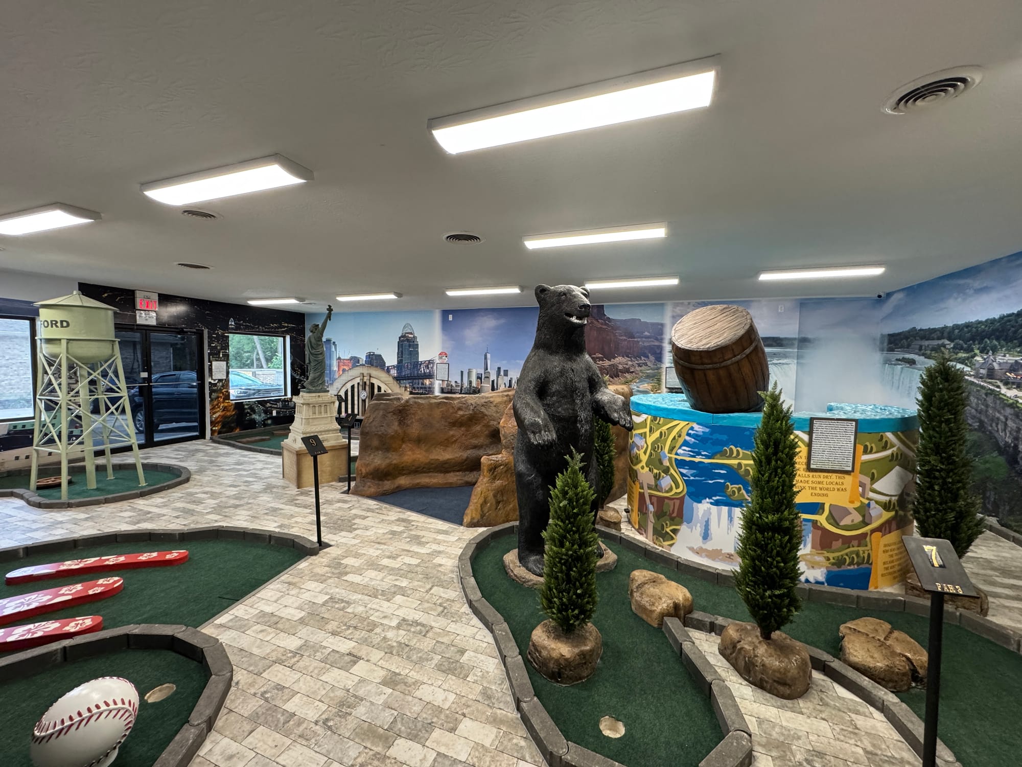 The mini golf course is surrounded by murals of different travel locations