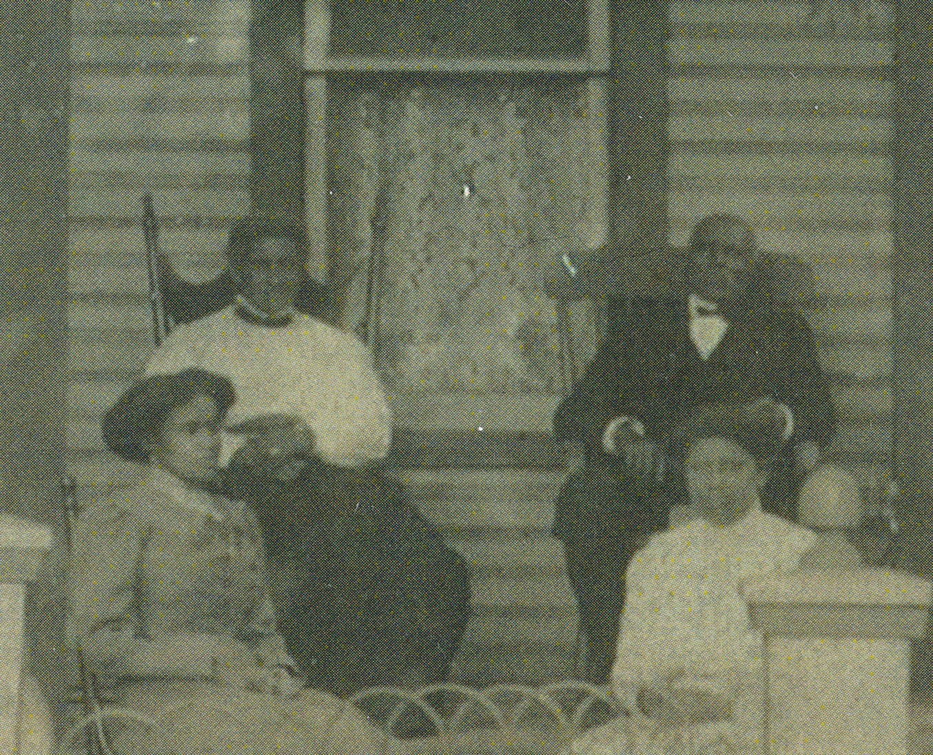 Sarah and Perry Gibson sit in rocking chairs on the porch of their daughter’s home around 1910 with daughter Daisy (Gibson) Bedenbaugh and daughter-in-law Maude (Ayers) Gibson.&nbsp; 