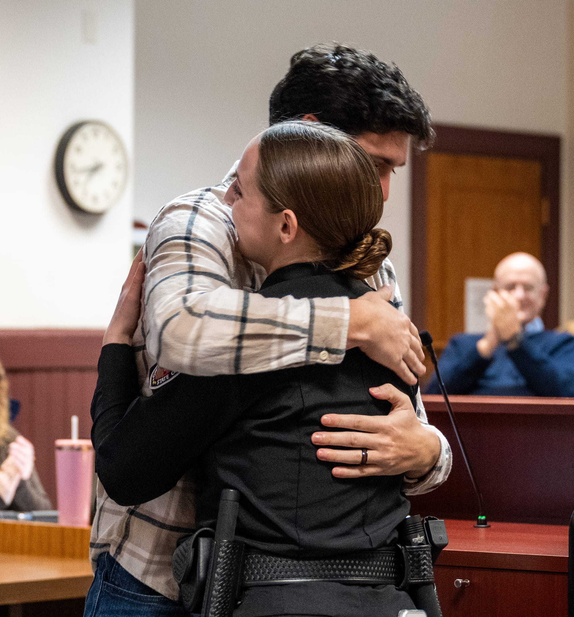After pinning her badge, Lonnie hugs Elana while her family cheers in the crowd.
