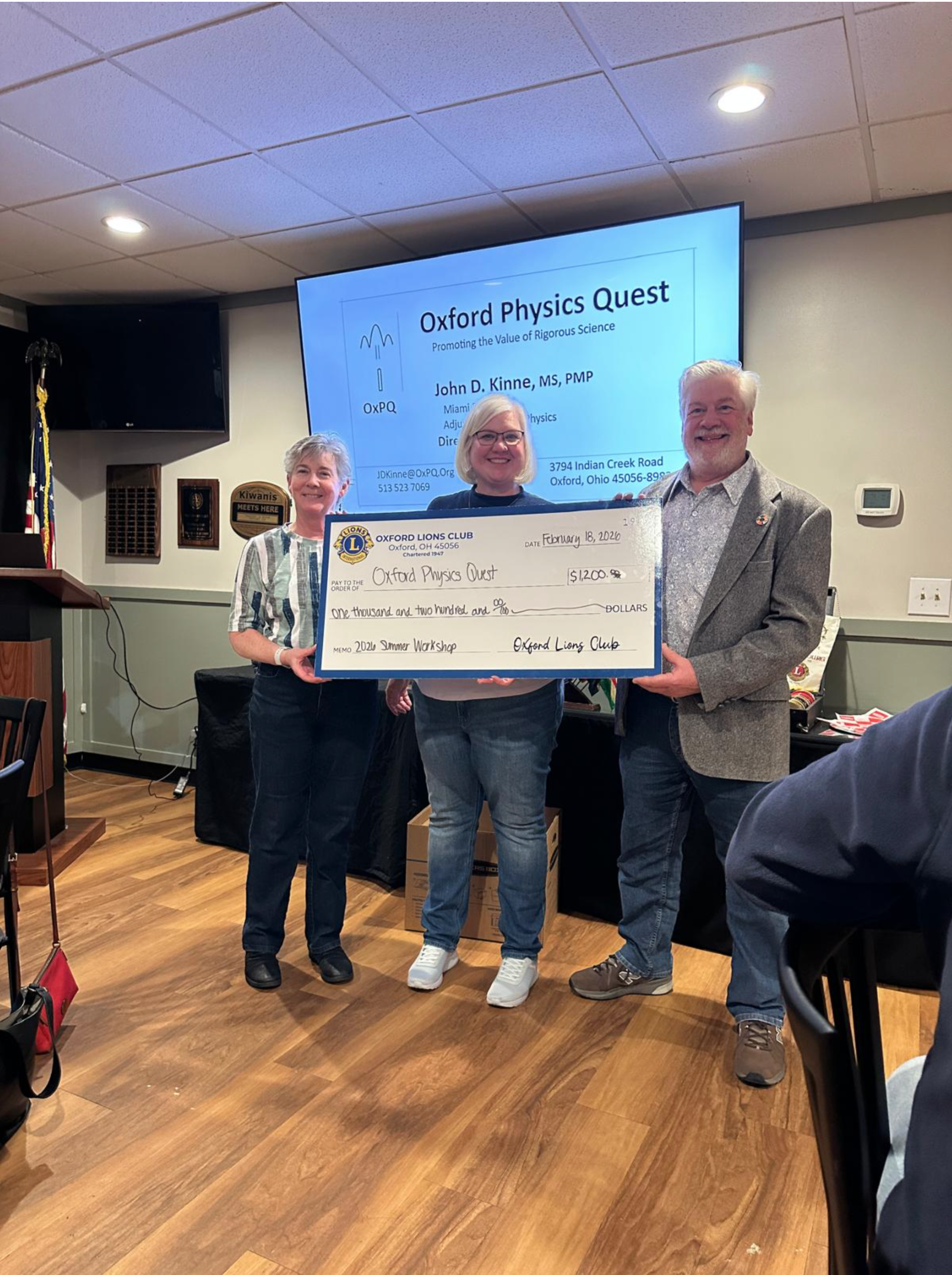 Chrissy Brunner (center) presents a check from the Oxford Lions Club for Oxford Physics Quest to Director John Kinne and Treasurer Bobbi Kinne.