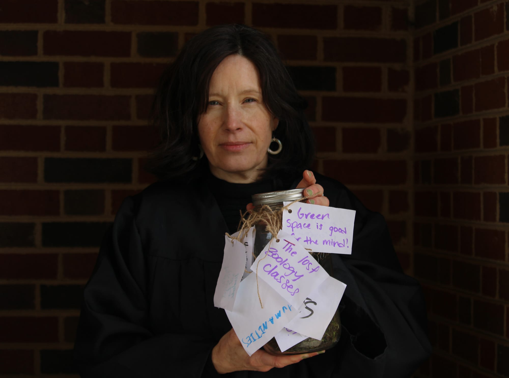 English professor Cathy Wagner holds the urn for a photo during a “funeral” for Cook Field