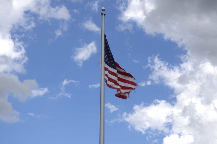 An American flag against a blue sky with clouds