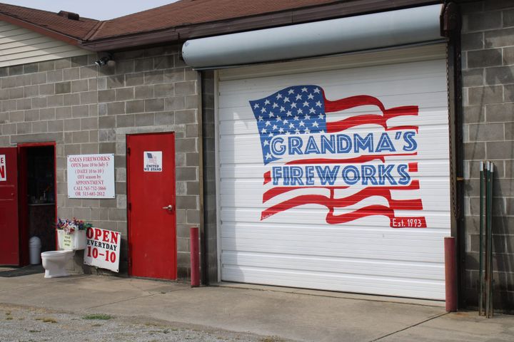 A building with its white garage door painted with the merican flag and "grandma's fireworks."