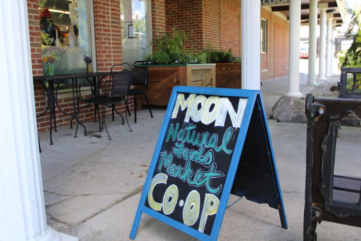 A blue A-frame sign reads "MOON Co-op natural foods market"