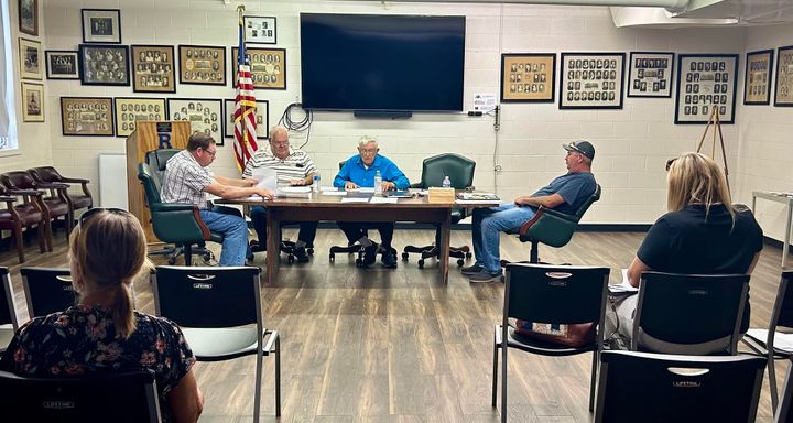 Members of Reily Township Trustees sit in meeting room around oval wooden table discussing resolutions and community complai