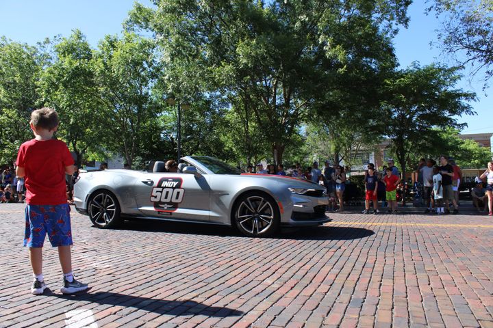 A little kid in red stares at Indy 500 pace car during the Freedom Festival Parade. Photo by Taylor Stumbaugh
