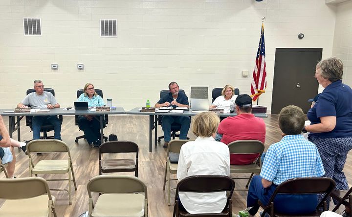 Four Milford Township Trustees, two men and two women, listen to woman in blue talk about the dog ban in cemeteries.