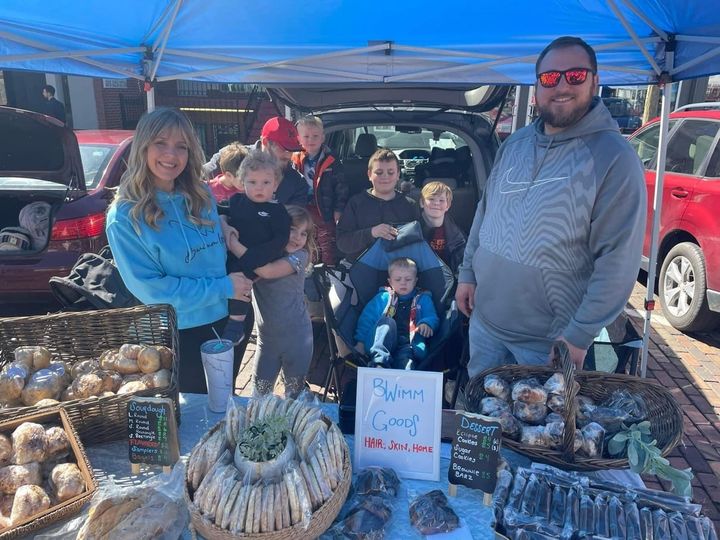 Brittney Wimmer and Ben Wimmer stand behind a baked goods stand with their six kids