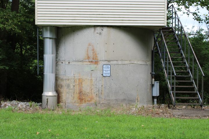 A concrete water production well with metal stairs on the right and a wide metal pipe on the left