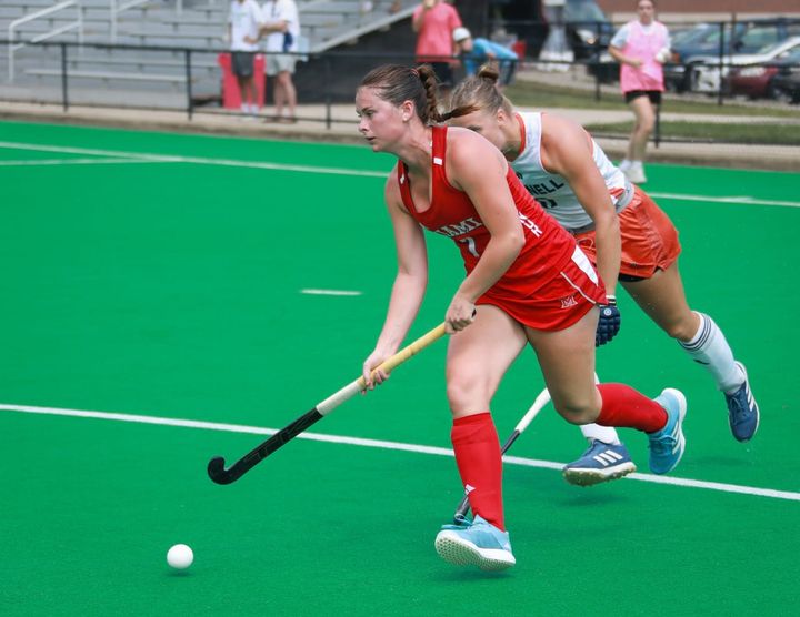 Carlie Servis chases after a ball on a bright green field