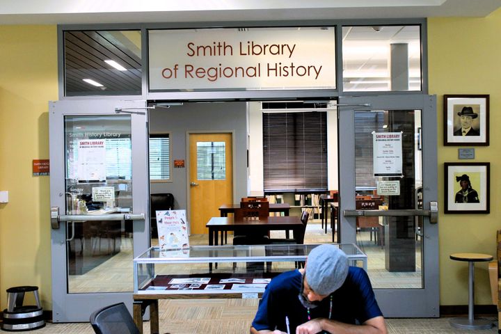 A man works in front of the Smith Library of Regional History entrance