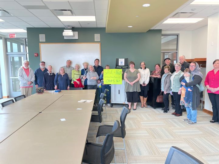 Dozens of residents pose for a photo holding a "Save the IRA sign"