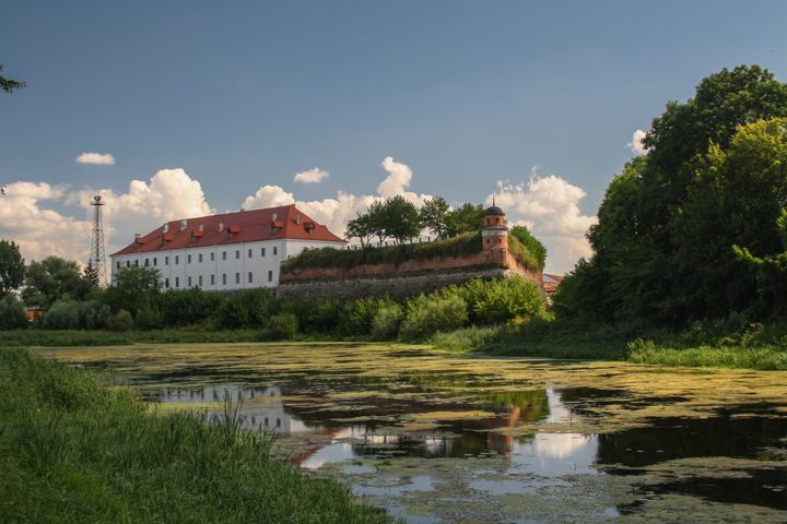 A white castle with a red roof seen across a body of water