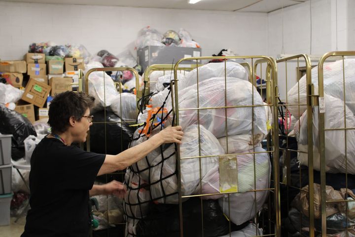 Shana Rosenberg pushes a cart of clothing in a warehouse