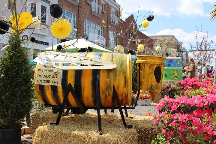 A rain barrel and five gallon bucket painted and arranged to look like a bee