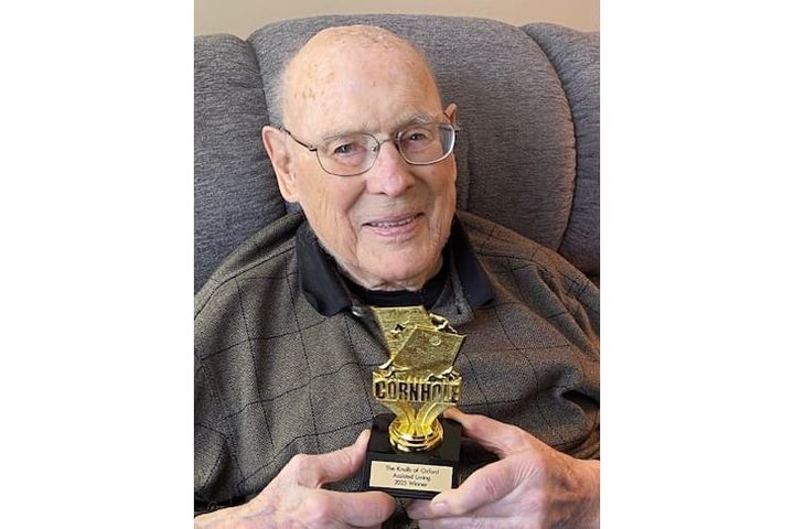 James M. Minium holds a cornhole champion trophy