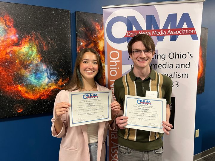Taylor Stumbaugh and Sean Scott hold certificates in front of an ONMA banner