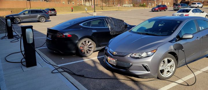 Two electric vehicles plugged into a charging station at Miami's Pearson Lot