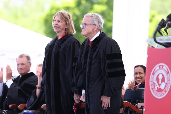 Mike and Fran DeWine stand on stage at Miami University's spring graduation, wearing black gowns as they receive hononary degrees.