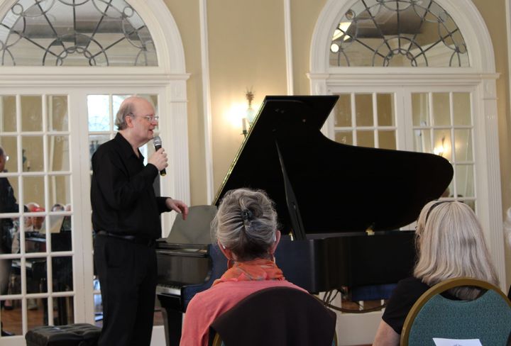 Bruce Murray stands next to a piano