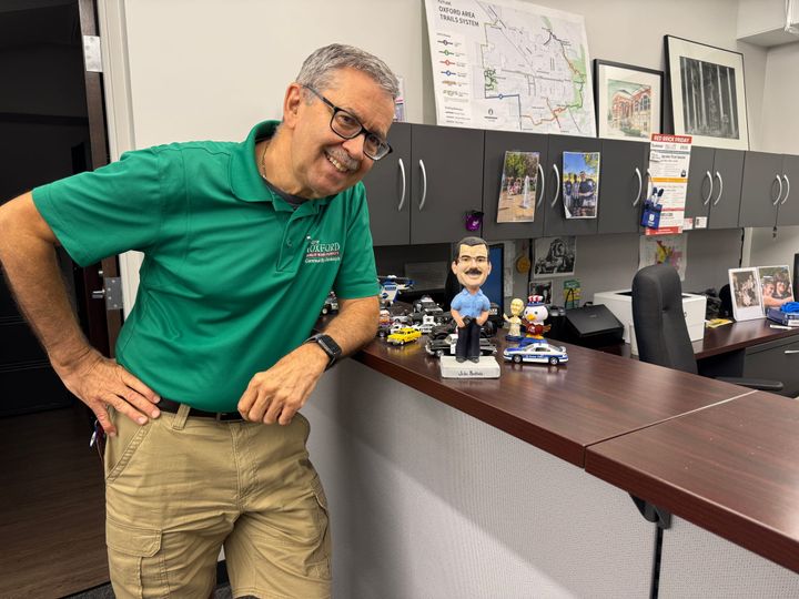  John Buchholz standing by a bobblehead lookalike, gifted from his daughter, on his desk.