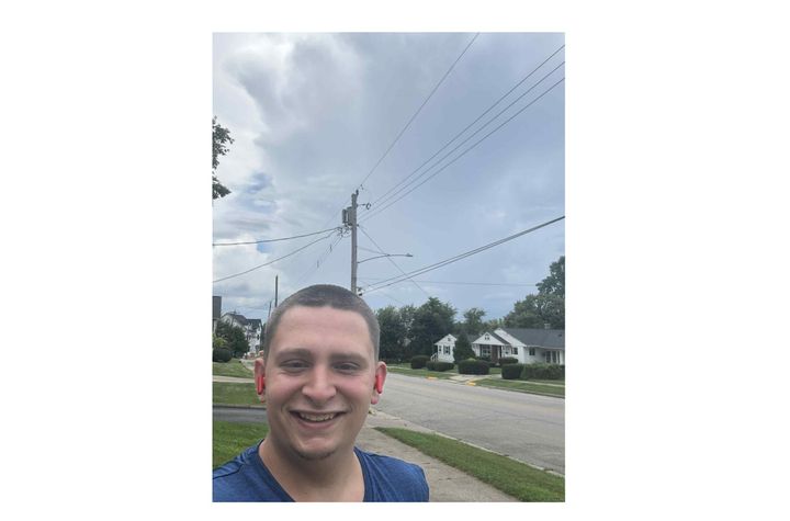 Trey Walzer stands in front of a storm cloud