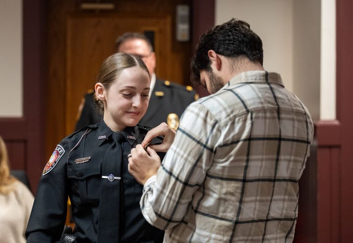 Lonnie Schwartz, Elana’s husband, pins her badge on her uniform.