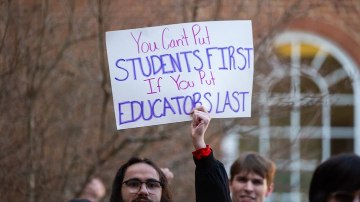 A student protests with a sign that reads "You can't put students first if you put educators last."