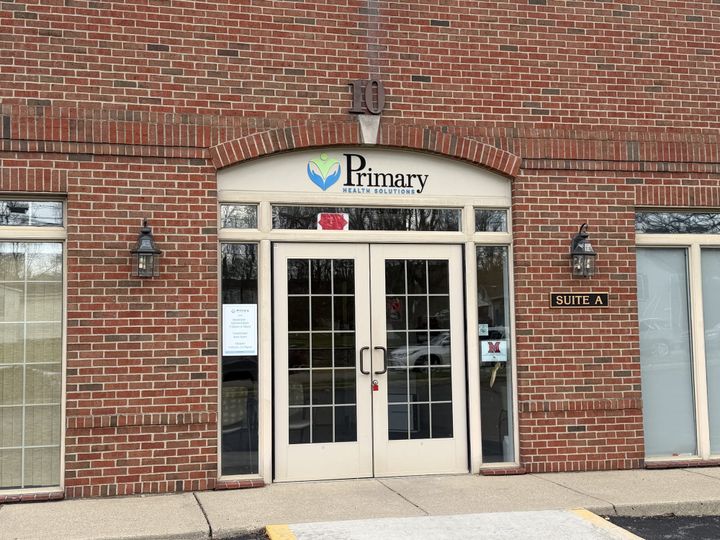 A brick building with two glass sotres and a sign over that says Primary Health Solutions