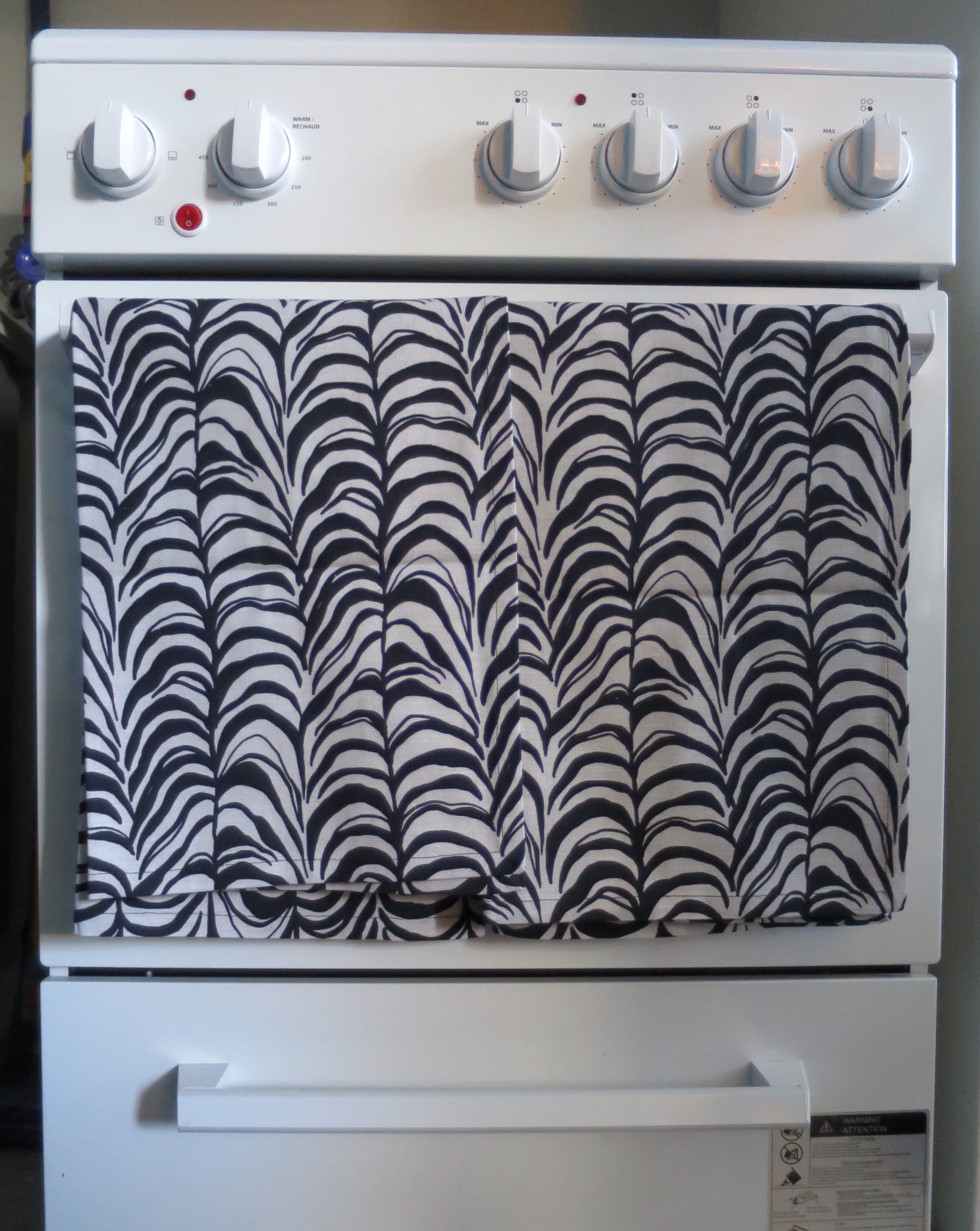 Two tea towels hanging on an oven door handle.