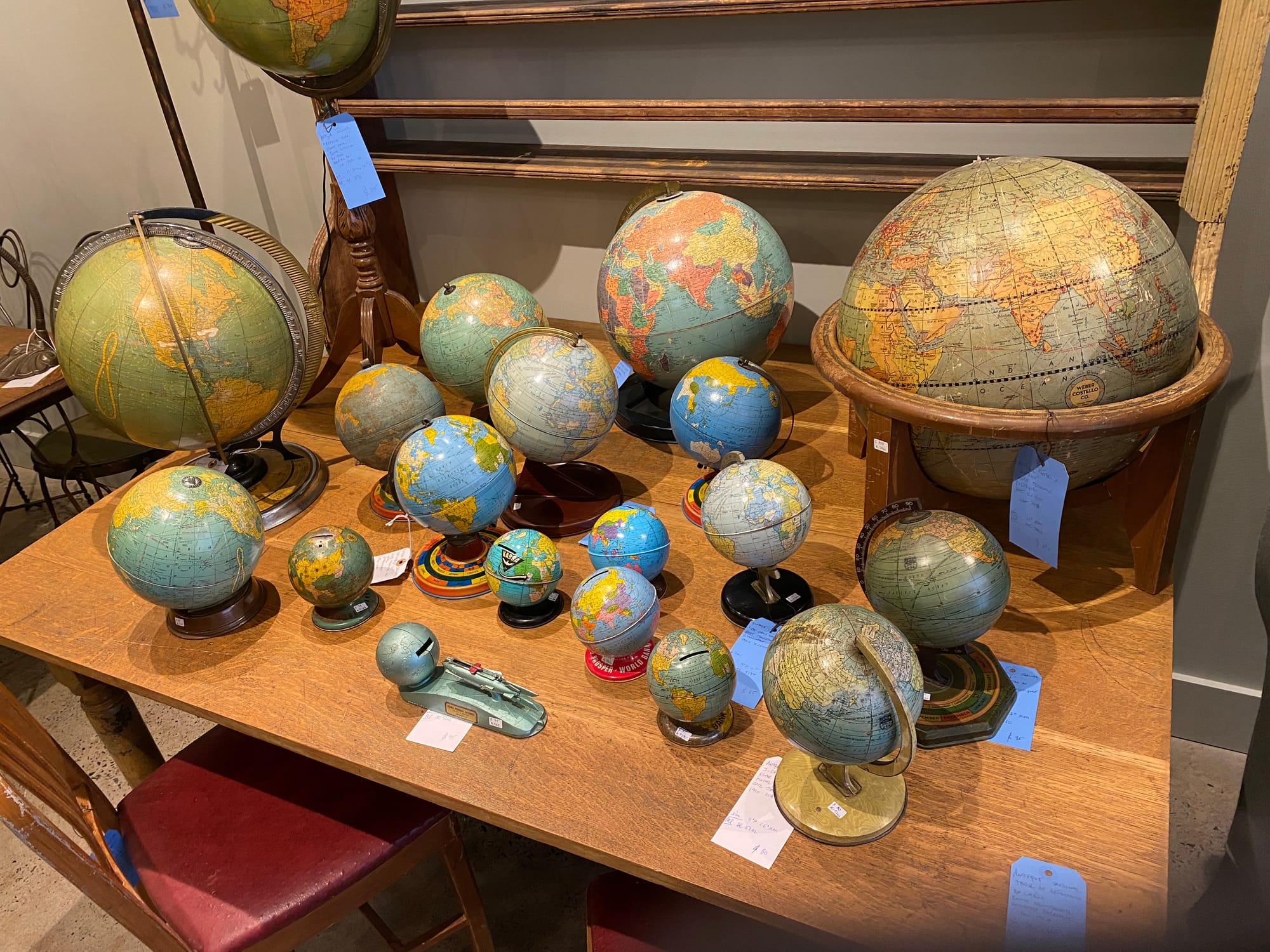 Vintage globes of various sizes on a wooden table.