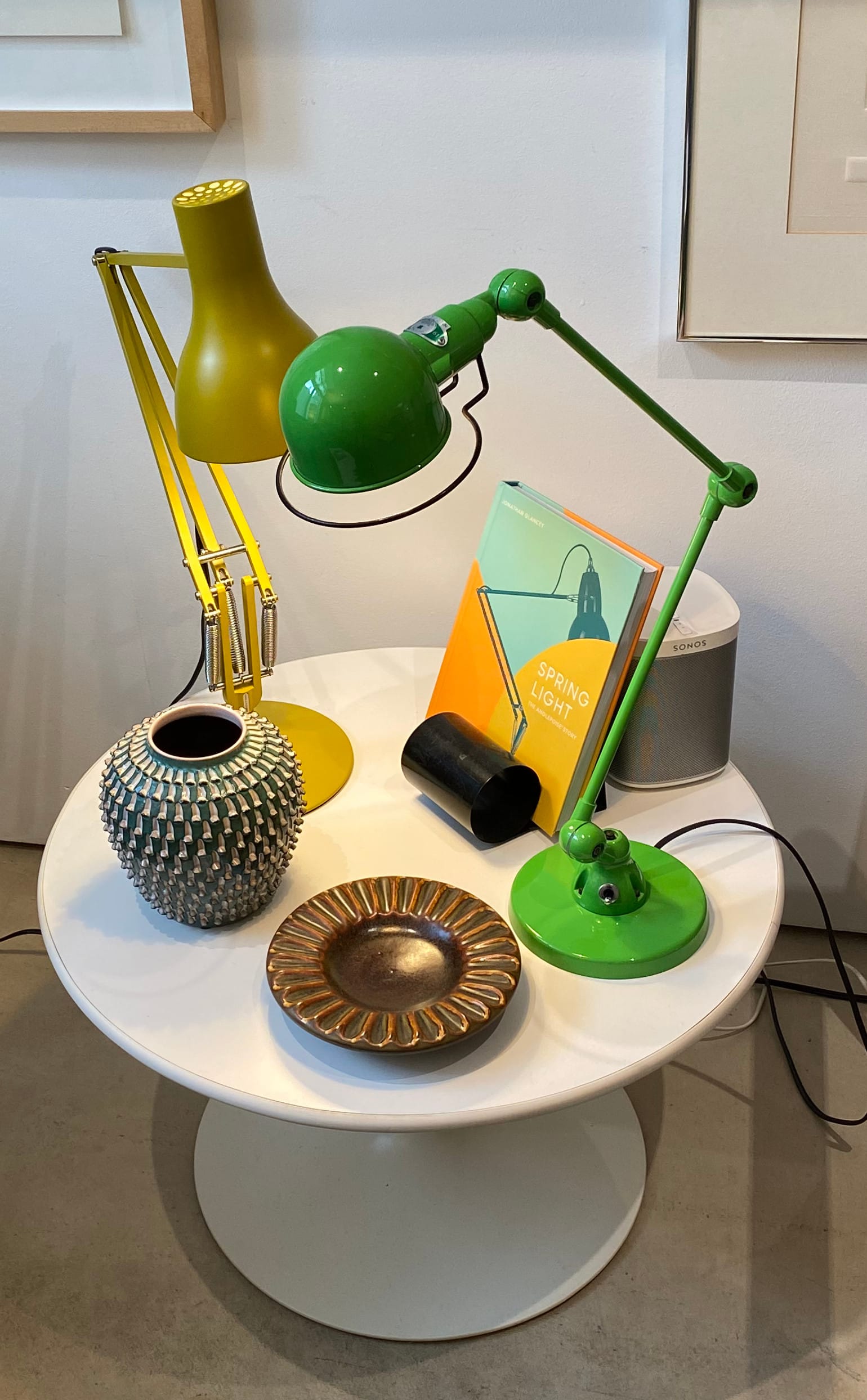 A side table with an eclectic assortment of objects, including two task lamps.