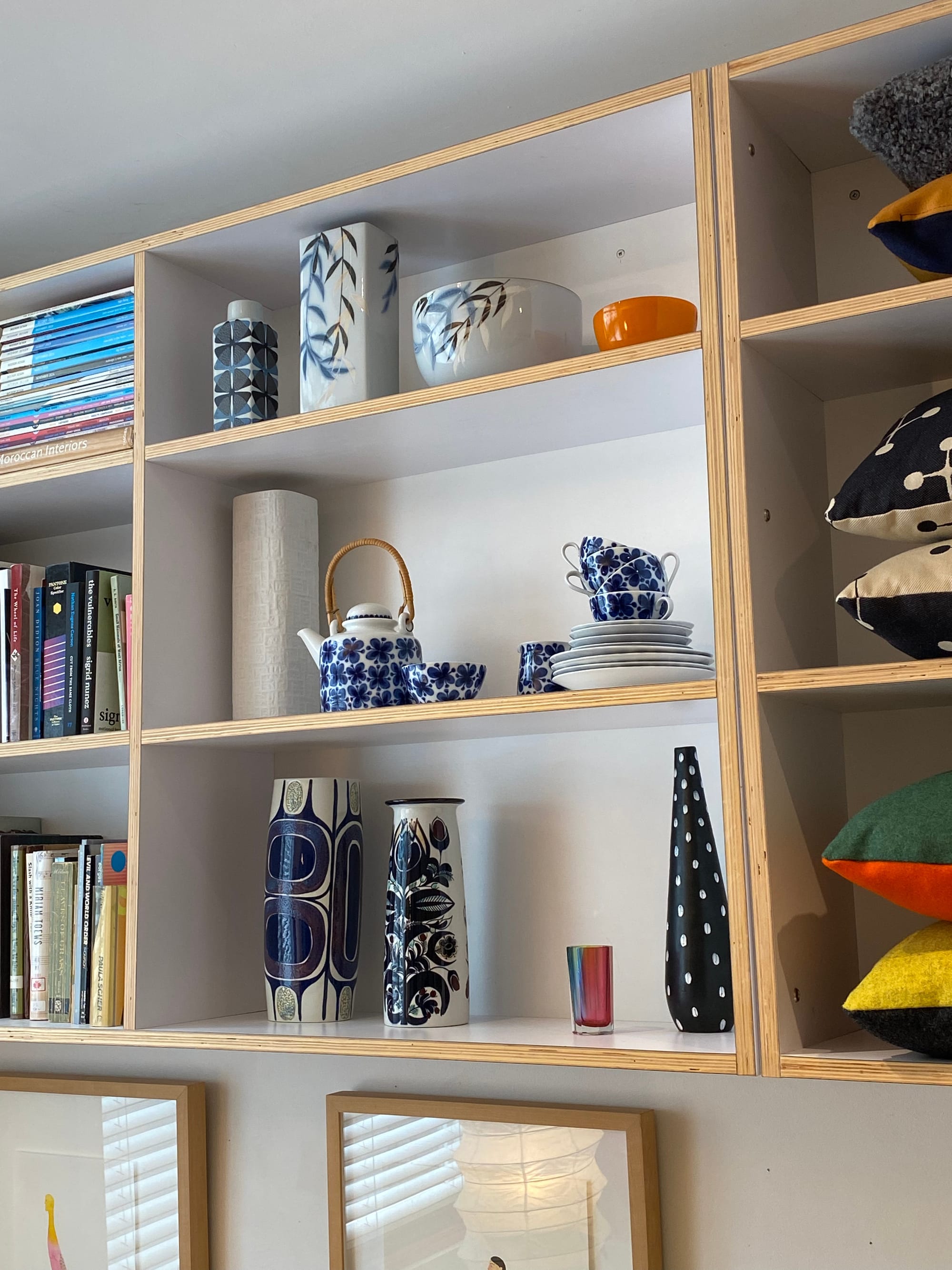 Three open shelves displaying vases, bowls, tea cups and a teapot.